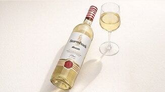 Fles Stormhoek Moscato witte wijn naast een gevuld wijnglas op een lichte ondergrond.