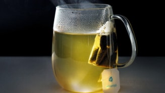 Warm kopje thee met theezakje in een glas.