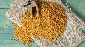 Fregola sarda, geroosterde pastabolletjes uit Sardinië in houten lepel