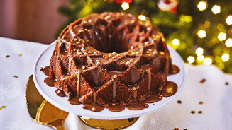Chocoladecake met glazuur en parels op een decoratieve schaal voor kerstverlichting.