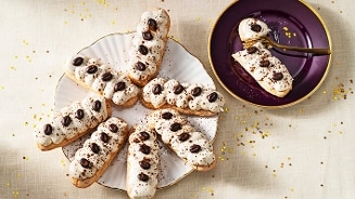Dessertschaal met tiramisubiscuitjes, naast een bord met een deels gegeten biscuitje.