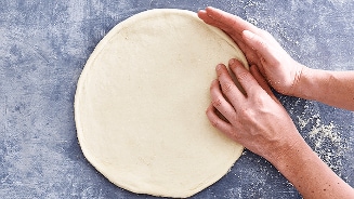 Pizzadeeg dat met de handen wordt gevormd.