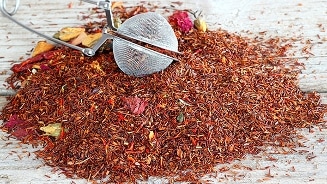 Losse rooibos thee met thee-ei op houten achtergrond.