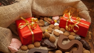 Pakjesavond met Sinterklaasgeschenken, kruidnoten, chocoladeletters en snoepgoed op jute zak