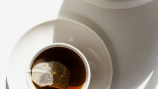 Kopje thee met theezakje en theepot in de zonlicht.