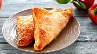 Verse appelflappen op een bord met appels op de achtergrond