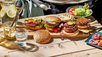 Vers belegde burgers bij een gloeiende BBQ, klaar om te grillen na het BBQ aansteken