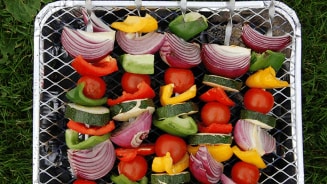 Volle buitentafel met gegrild vlees en salades tijdens een zomerse BBQ, net aangestoken