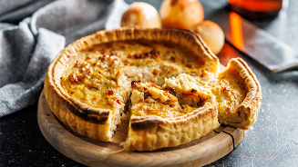 Hartige quiche op een houten snijplank, met een paar gesneden stukjes.