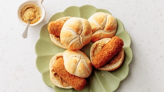 Vier broodjes kroket op een groen bordje met een kommetje met mosterd er bij