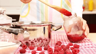 Zelfgemaakte frambozenjam bereiden in de keuken met verse frambozen.
