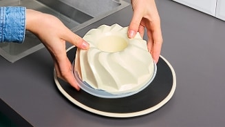 Vanille bavarois in een decoratieve vorm op een bord, klaar om geserveerd te worden.