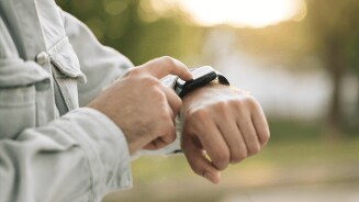 Persoon bedient smartwatch op pols in buitenomgeving