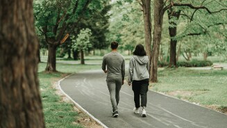 Twee mensen wandelen samen over een pad in een groene parkachtige omgeving