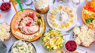 Gevulde eieren, diverse salades, gesneden vleeswaren, groenteschotel en brood op een feestelijk gedekte tafel.