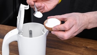Man voegt poeder toe aan een elektrische waterkoker.