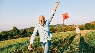 Twee volwassenen die in een grasveld een vlieger oplaten met een mooie natuurlijke achtergrond.