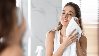Vrouw droogt haar gezicht af met een handdoek in de badkamer