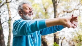 Persoon in blauwe trui die buiten stretchoefeningen doet