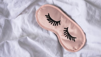 Slaapmasker met wimpers op een wit laken