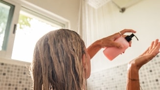 Vrouw gebruikt shampoo onder de douche