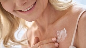 Vrouw brengt crème aan op haar schouder