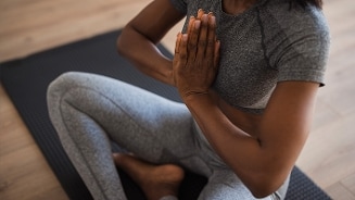 Vrouw in grijze sportkleding doet yogahouding op een mat