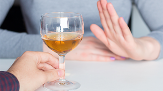 Hand die een glas drank aanbiedt terwijl een andere hand het aanbod afwijst.