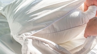 Witte kussen met hand die de kussensloop aanpast