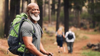Man met groene rugzak wandelt in het bos