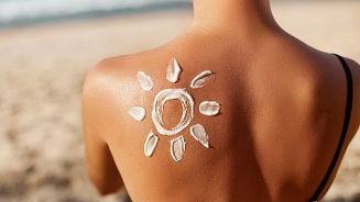 Zonnecrème in de vorm van een zon op een rug op het strand