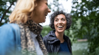 Twee personen wandelen in een groen park met wazige gezichten.