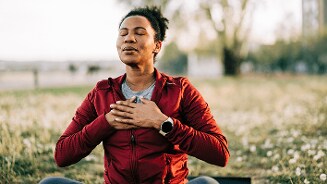 Persoon in rode jas bezig met meditatie in een veld