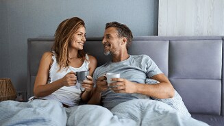 Twee mensen zitten in bed en drinken koffie.