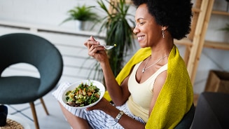 Vrouw eet salade in een gezellige kameromgeving