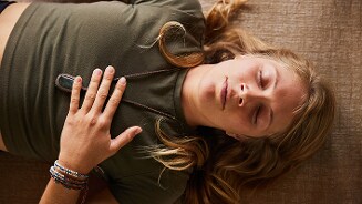 Liggend persoon met hand op borst en houten vloer op de achtergrond