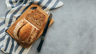 Gesneden bruin brood op een houten snijplank met een mes