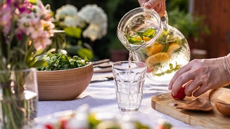 Ingeschenk karaf met vers fruit en kruiden op een zomerse tafel.