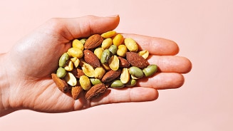 Hand met een mix van noten en zaden, waaronder amandelen en pistachenoten.