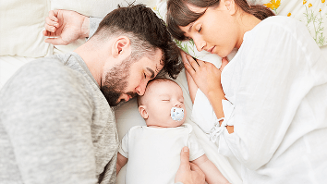 Ouders liggend naast een baby op bed