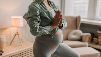 Zwangere vrouw doet yoga in de woonkamer