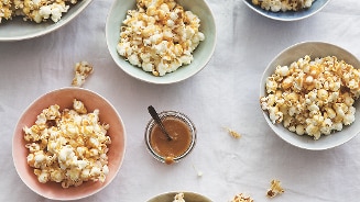 Verschillende kommen met karamelsaus en popcorn op een tafel.