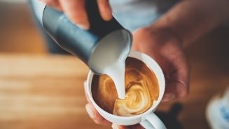 Barista giet melkschuim in een kopje koffie.