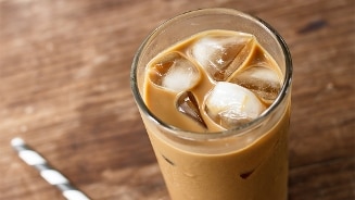 Glas ijskoffie met ijsblokjes op een houten tafel