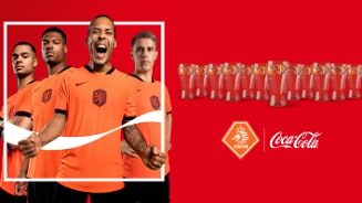 Voetbalspelers in oranje KNVB-tenues met promoglasses van Coca-Cola op een rode achtergrond, inclusief KNVB- en Coca-Cola-logo.