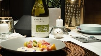 Gedekte dinertafel met een fles Cono Sur Bicicleta Sauvignon Blanc en een bord met een verfijnd gerecht.