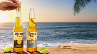 Twee flesjes Corona bier, één Corona Extra en één Corona Cero, met partjes limoen op een houten tafel bij zee tijdens zonsondergang.