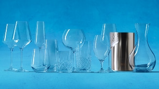 Assortiment van verschillende soorten glazen en een wijnkoeler op een blauwe achtergrond