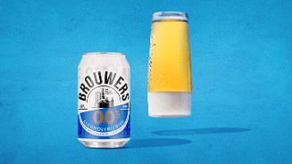 Blik Brouwers 0.0% alcoholvrij bier naast een glas gevuld met alcoholvrij bier tegen een blauwe achtergrond