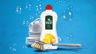 Fles AH Eco afwasmiddel citroen met een afwasborstel en schone witte borden en kopjes op een blauwe achtergrond met zeepbellen.